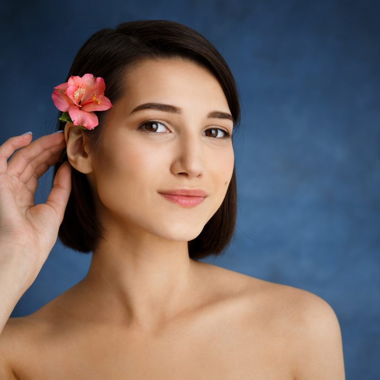 Picture of tender young girl with flower in hair over blue background
